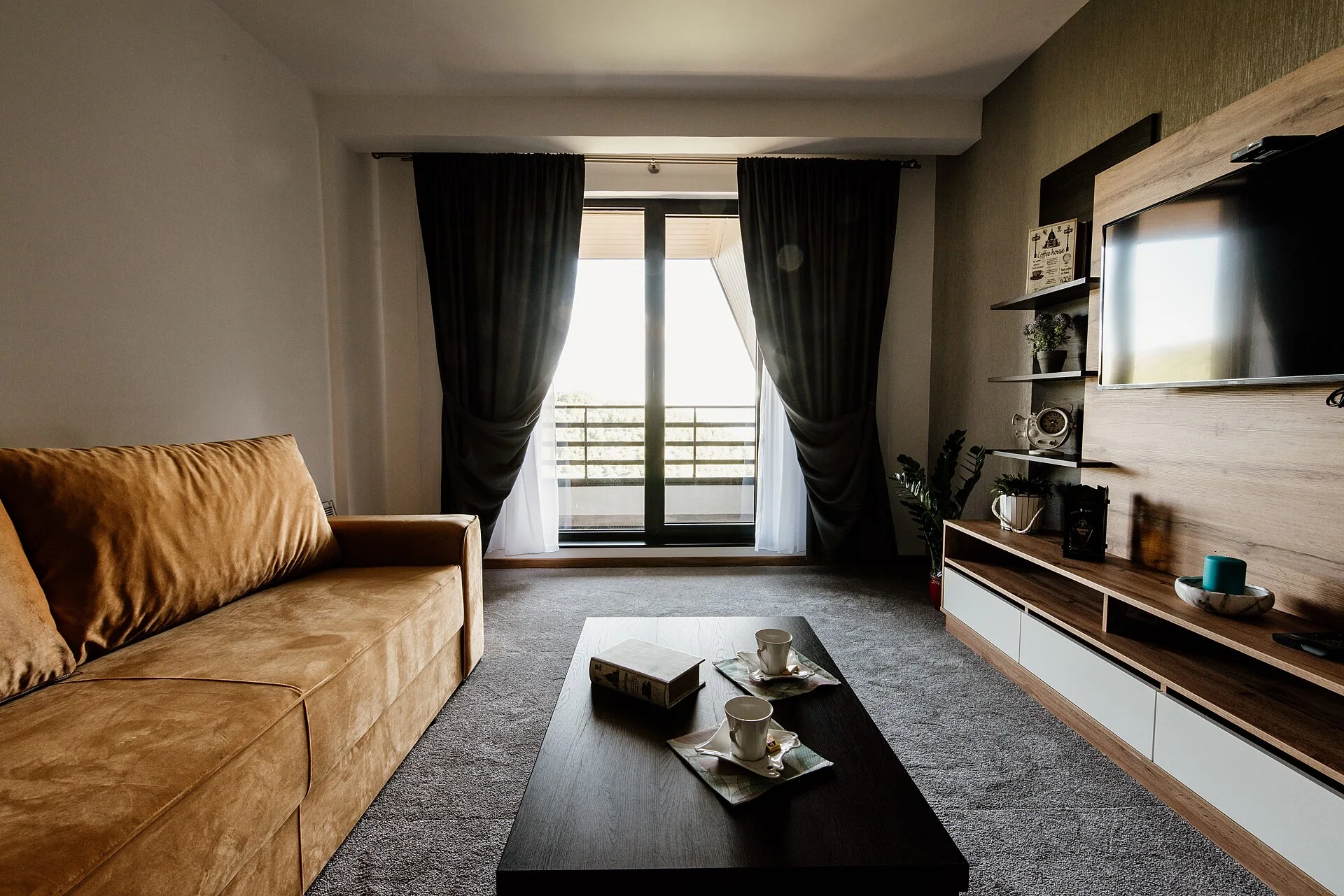 Soggiorno luminoso con divano beige, tavolo e porta bianca